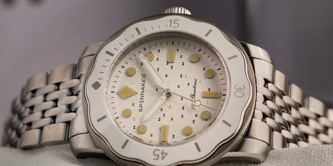 Montre en acier inoxydable avec cadran blanc et aiguilles jaunes, bracelet à maillons.