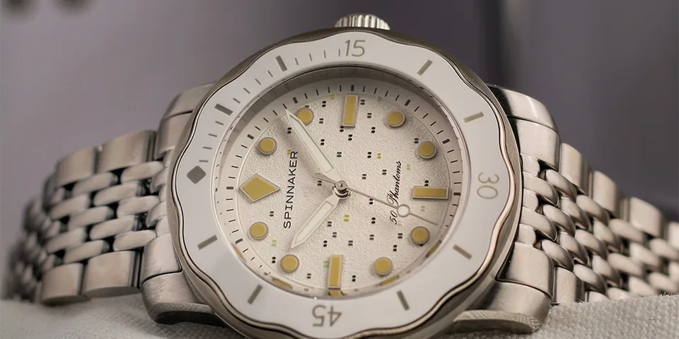 Montre en acier inoxydable avec cadran blanc et aiguilles jaunes, bracelet à maillons.