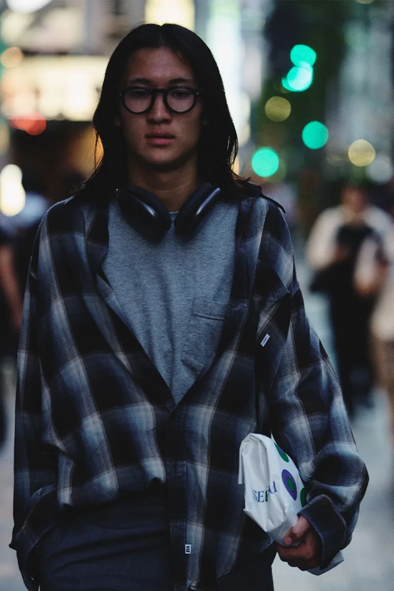 Homme avec lunettes et écouteurs, portant une chemise à carreaux.