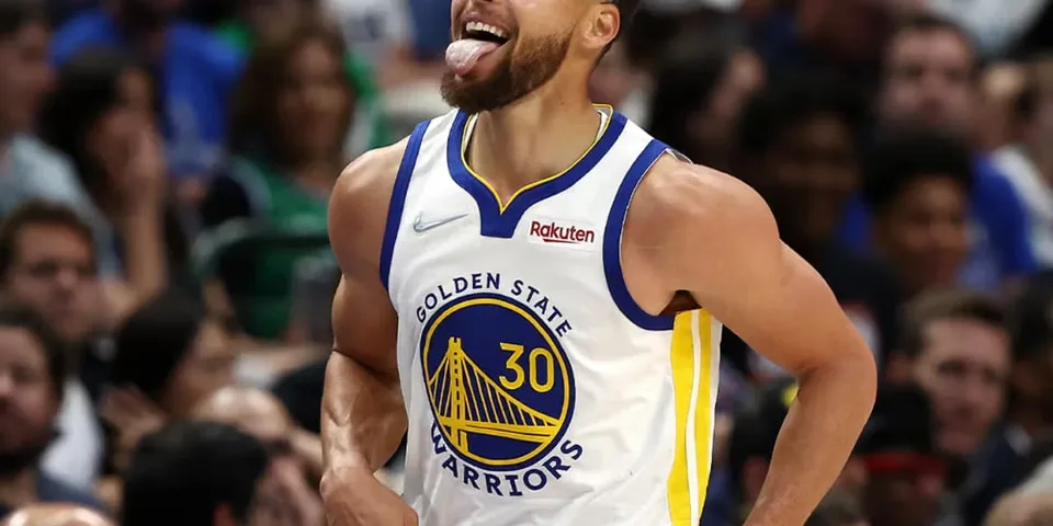 Joueur de basket célébrant avec langue tirée, maillot Warriors.