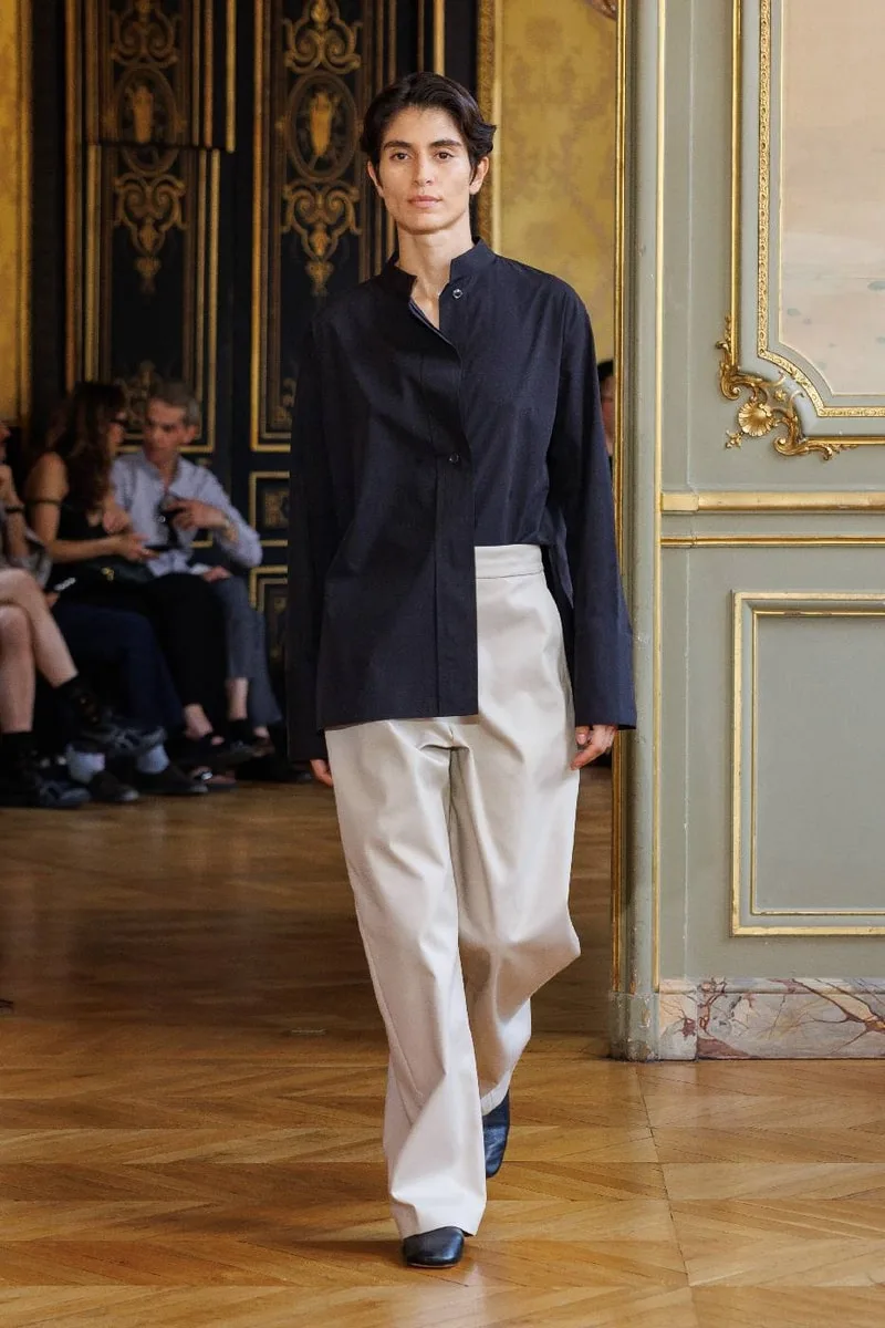 Personne défilant avec une tenue élégante dans un intérieur sophistiqué.