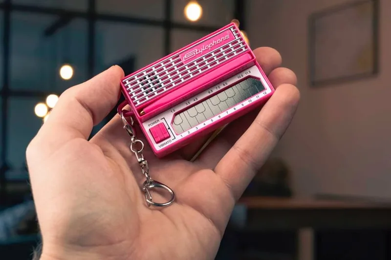 Petite radio rose en porte-clés tenue par une main