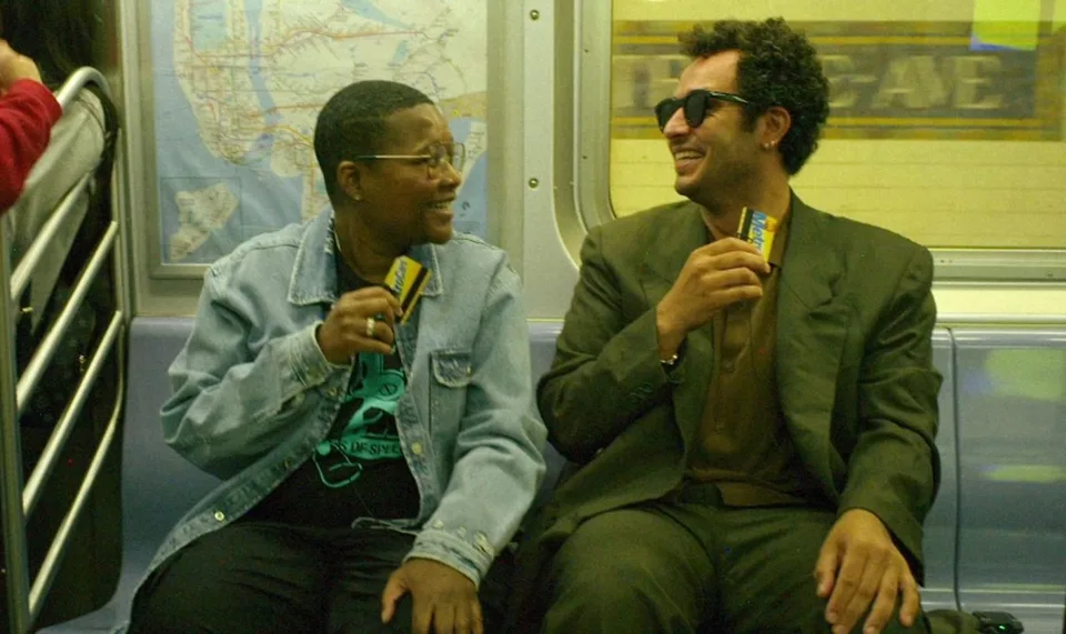 Deux personnes souriantes dans le métro tenant des cartes.