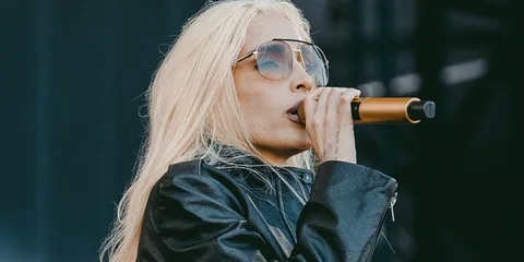 Personne blonde chante avec micro et veste en cuir