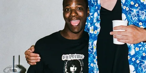 Deux personnes souriantes, portant des vêtements décontractés, dont un avec t-shirt Supreme.