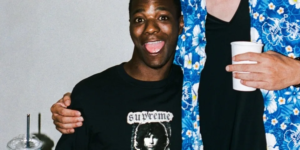 Deux personnes souriantes, portant des vêtements décontractés, dont un avec t-shirt Supreme.