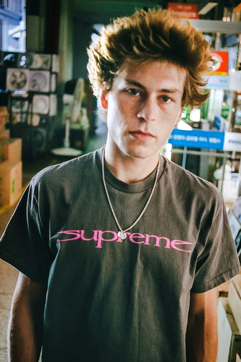 Jeune homme portant un t-shirt Supreme dans un endroit industriel.