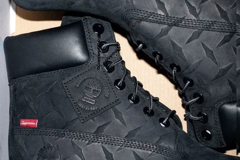 Bottes noires avec logos et étiquette rouge, détails en cuir.