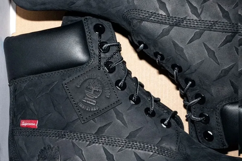 Bottes noires avec logos et étiquette rouge, détails en cuir.