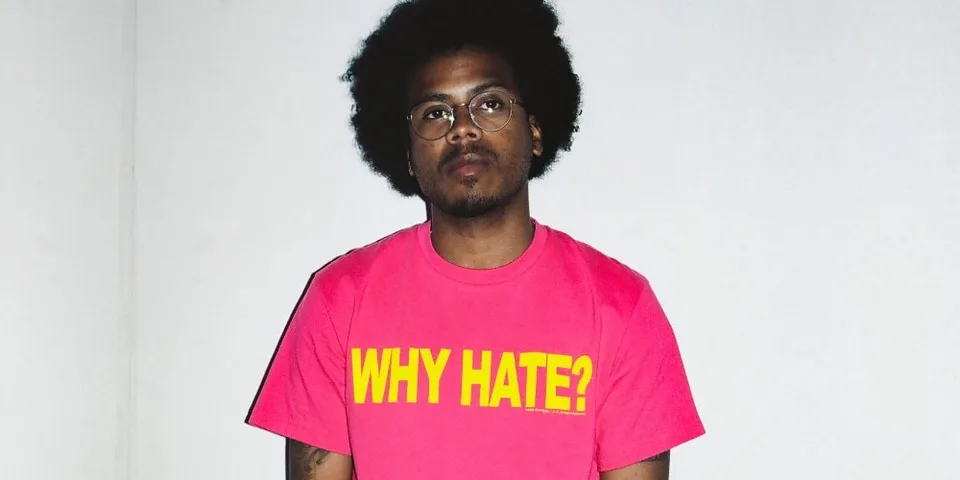 Homme portant un t-shirt rose avec texte 'WHY HATE ?' en jaune.