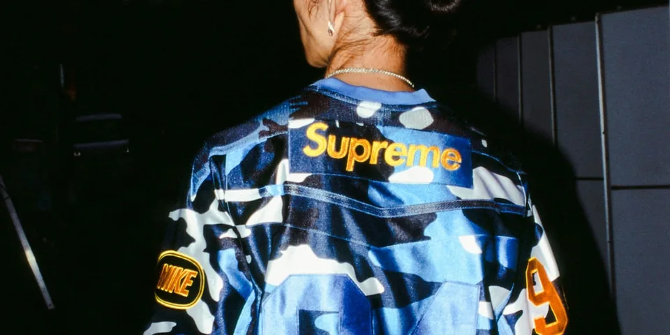 Personne portant une veste camouflage Supreme et Nike.
