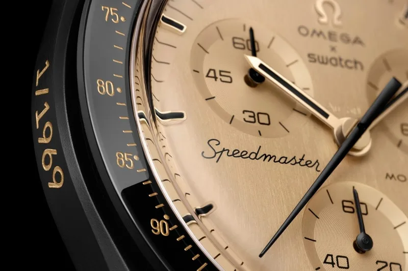 Vue rapprochée d'une montre Speedmaster Omega Swatch, cadran beige.