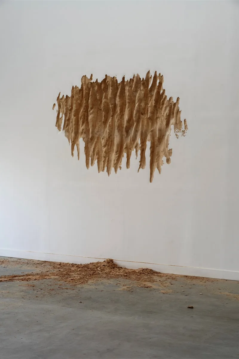 Mur blanc avec texture marron et matériaux au sol.