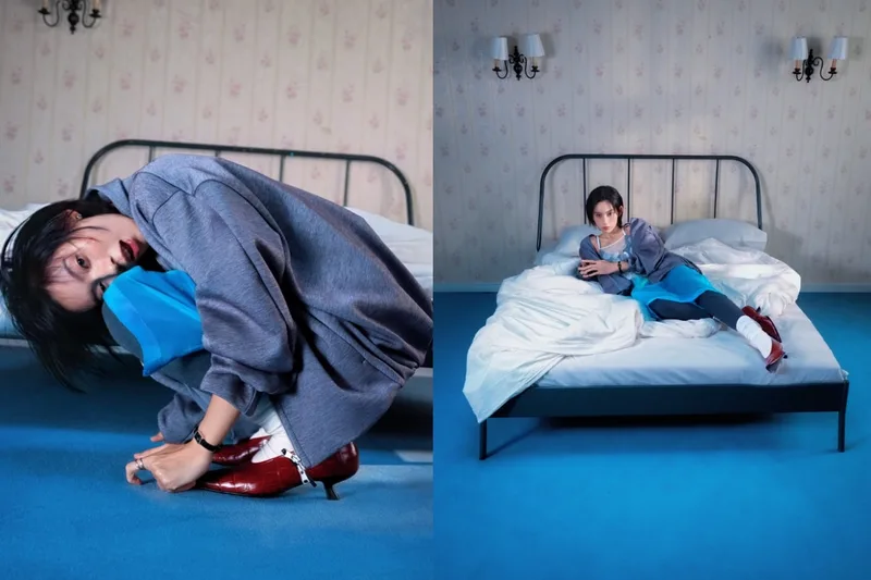 Femme en pull gris posant dans une chambre avec un sol bleu.
