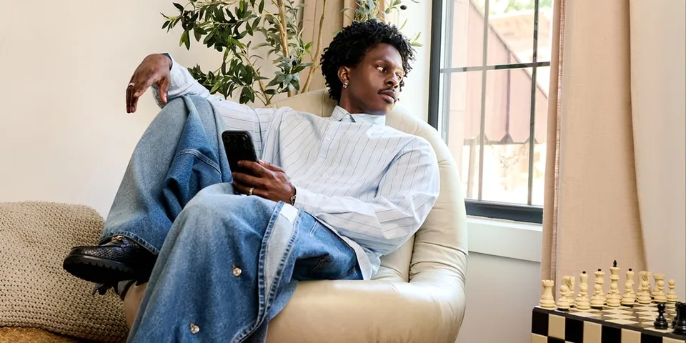 Personne assise, téléphone en main, devant un échiquier.
