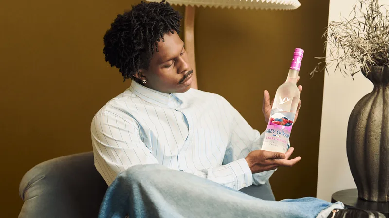 Homme observant une bouteille de vodka, tenu assis dans un fauteuil.