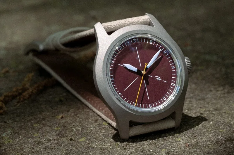 Montre-bracelet avec cadran marron sur fond gris, aiguilles et indicateurs visibles.