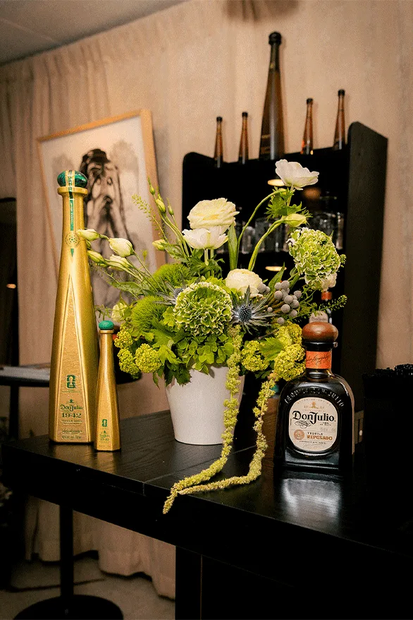 Bouteilles de tequila et bouquet de fleurs sur une table.