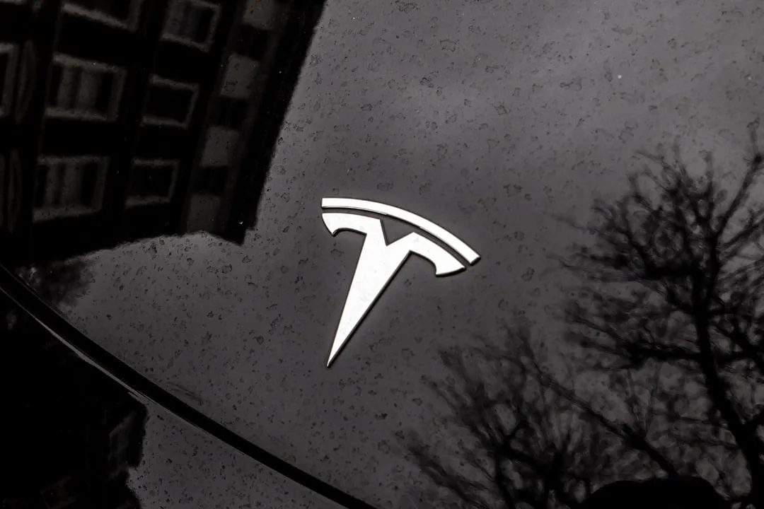 Logo Tesla sur une voiture noire réfléchissante.