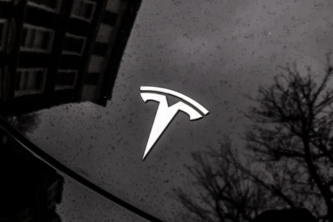 Logo Tesla sur une voiture noire réfléchissante.