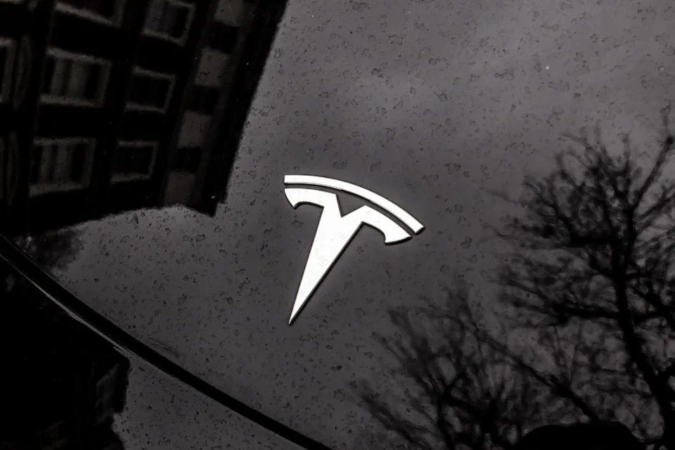 Logo Tesla sur une voiture noire réfléchissante.