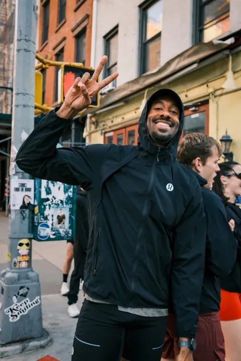 Homme souriant en tenue de sport, levant deux doigts.