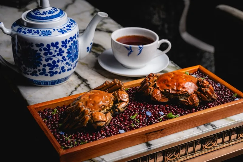 Crabes cuits sur des haricots rouges avec une théière et une tasse.