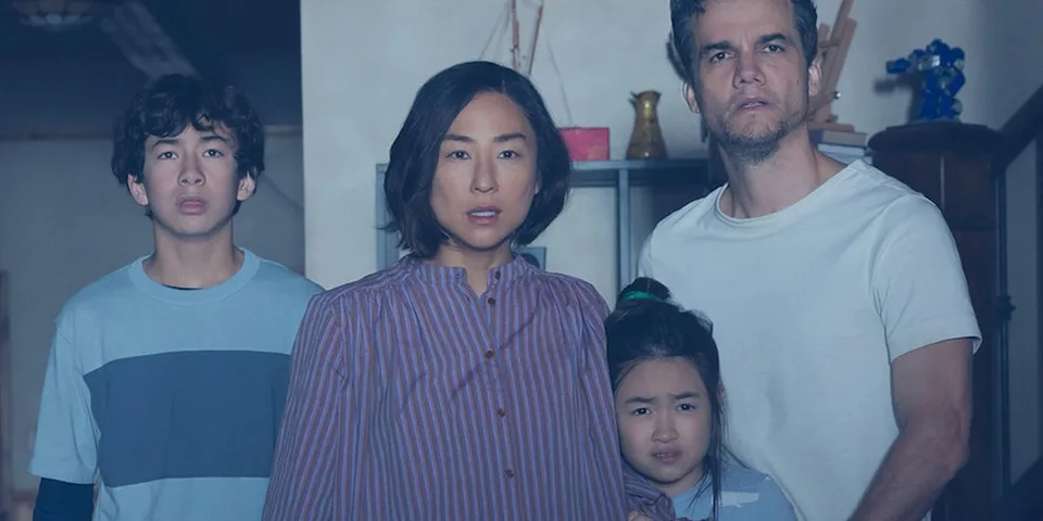 Famille de quatre personnes, trois adultes et un enfant, dans un salon.