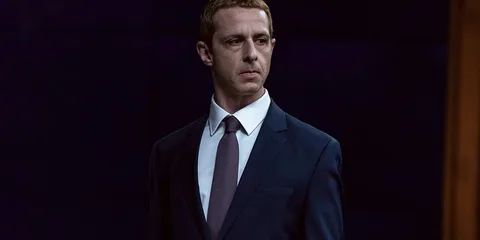 Homme en costume sombre sur fond noir.