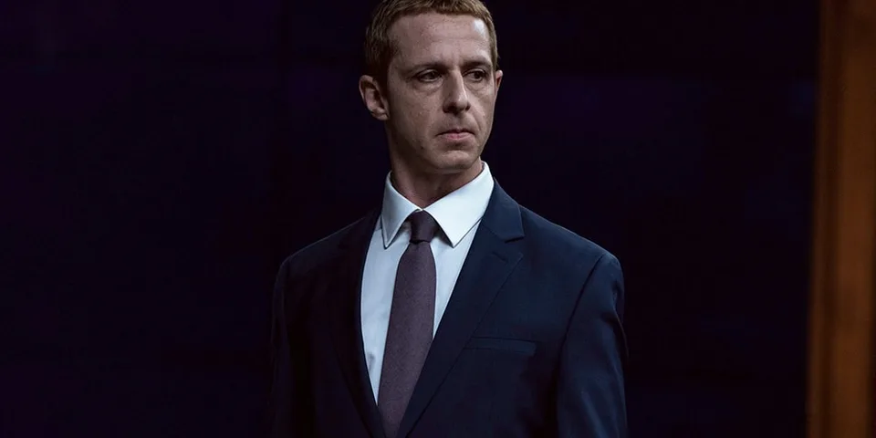 Homme en costume sombre sur fond noir.