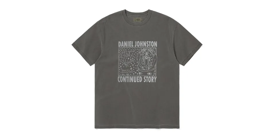 T-shirt gris avec dessin de Daniel Johnston, texte 'Continued Story' en blanc.