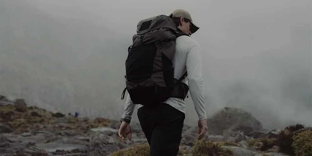 Personne en randonnée dans un paysage montagneux et brumeux.