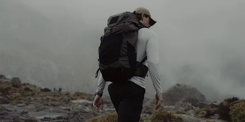 Personne en randonnée dans un paysage montagneux et brumeux.