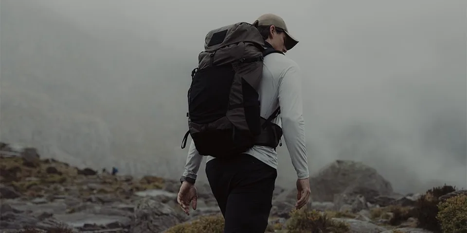 Personne en randonnée dans un paysage montagneux et brumeux.