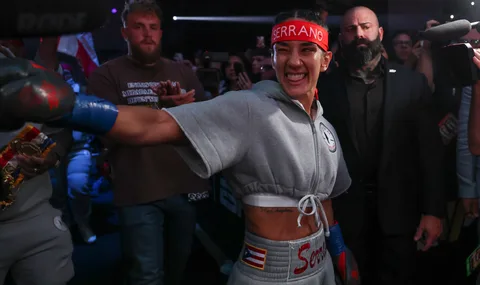 Femme boxeuse souriante avec bandeau rouge entourée de personnes en arrière-plan.