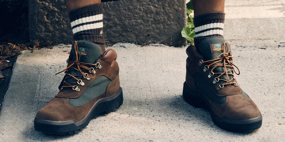 Bottes de randonnée marron avec chaussettes rayées sur un trottoir en béton.
