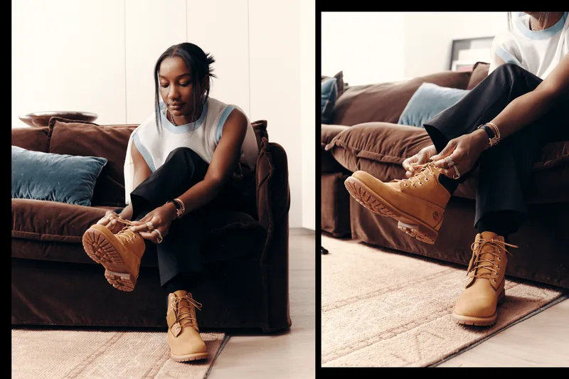 Personne assise attachant des bottes marron sur un canapé.