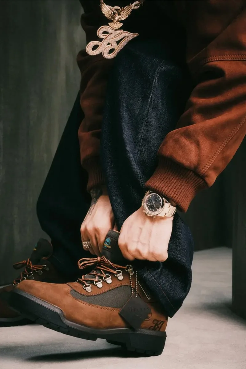 Personne portant des bottes marron et un survêtement avec une montre en or.