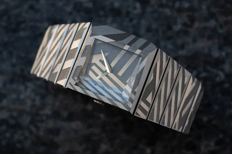 Montre à motif géométrique avec bracelet assorti sur fond sombre.