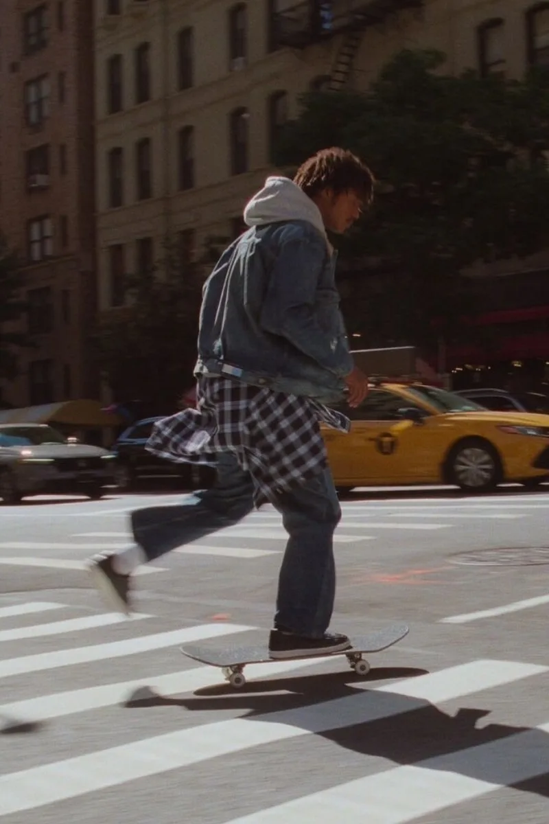 Un homme en skateboard traverse un passage piéton en ville.