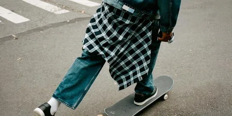 Personne en jeans faisant du skateboard sur la route.
