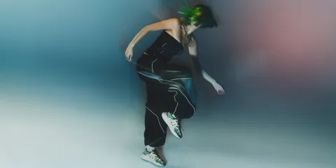 Personne en mouvement avec des baskets et des cheveux verts flous.