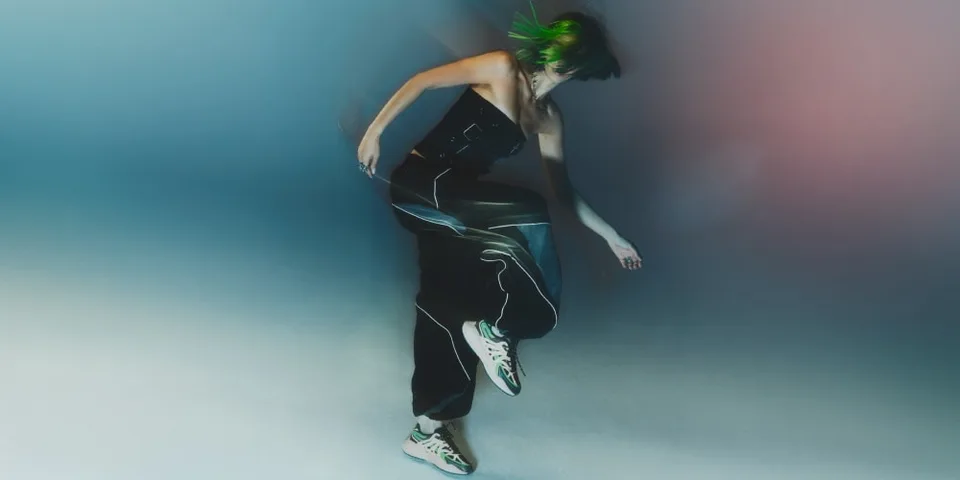 Personne en mouvement avec des baskets et des cheveux verts flous.