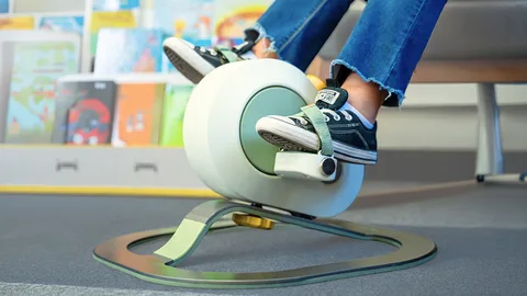 Enfant pédalant sur un vélo d’exercice adapté dans une salle de jeux.