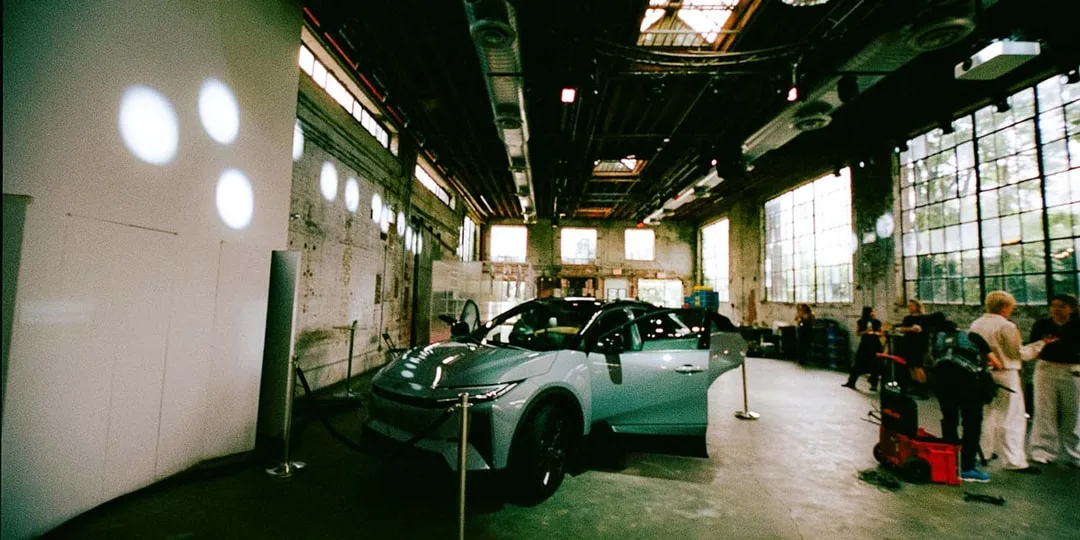 Un showroom avec une voiture moderne et des personnes autour de présentoirs.