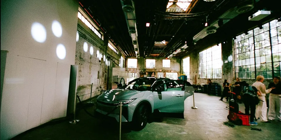 Un showroom avec une voiture moderne et des personnes autour de présentoirs.