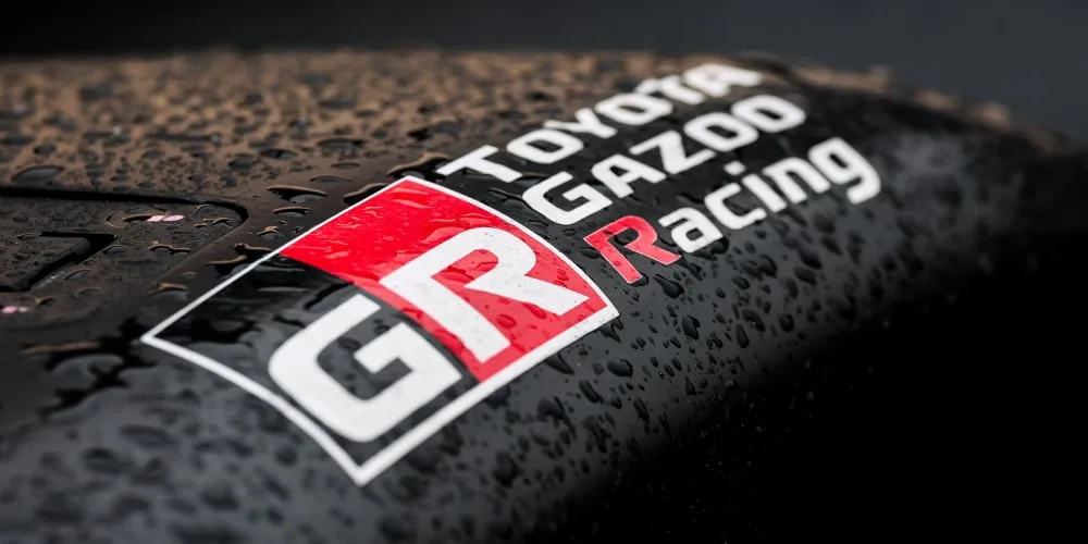 Logo Toyota Gazoo Racing sur une surface mouillée.