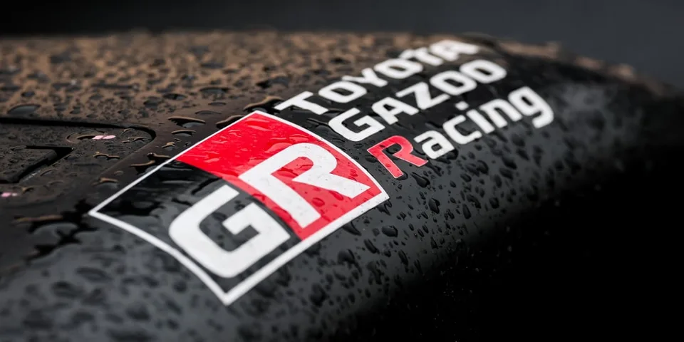 Logo Toyota Gazoo Racing sur une surface mouillée.