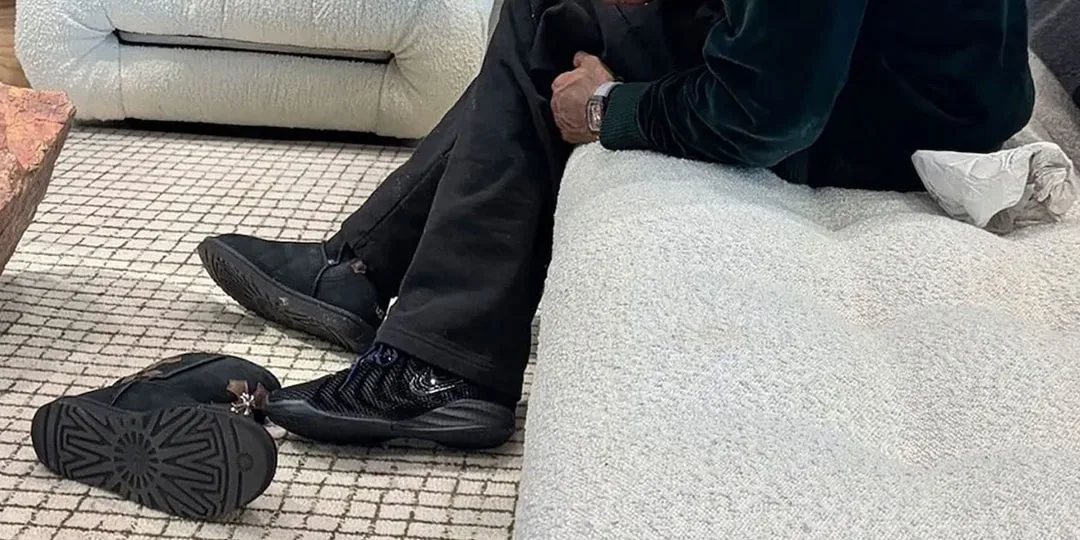 Personne assise sur un canapé blanc avec des baskets noires à côté.