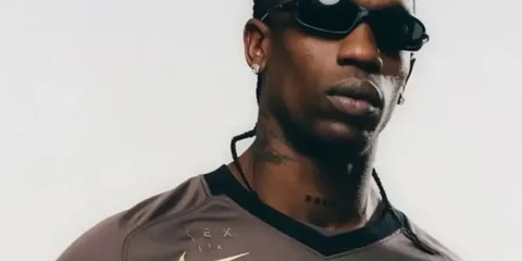 Homme en lunettes de soleil avec tresse portant un maillot marron.